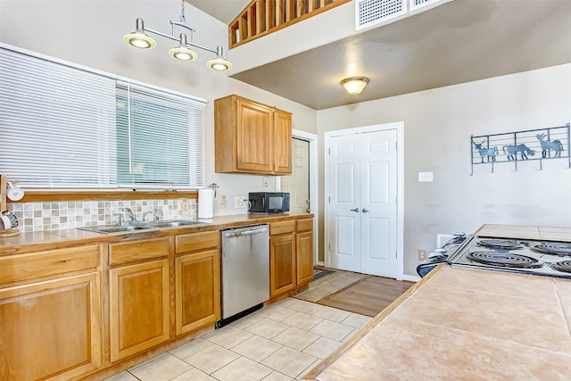 kitchen featuring tile counters, stainless steel dishwasher, light tile patterned flooring, a sink, and black microwave