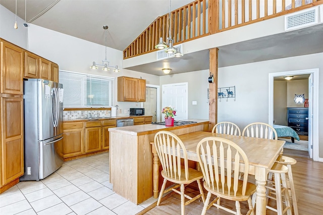 kitchen with visible vents, appliances with stainless steel finishes, a peninsula, light countertops, and high vaulted ceiling