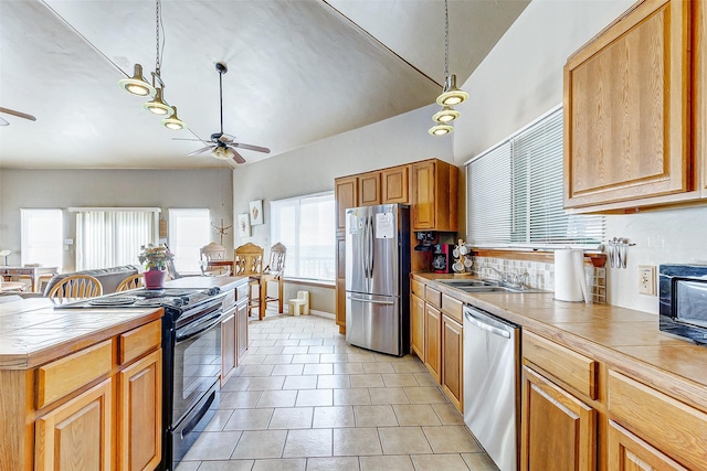 kitchen with ceiling fan, light tile patterned floors, stainless steel appliances, a sink, and tile counters