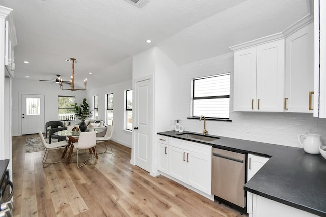 kitchen with dark countertops, white cabinetry, a sink, and stainless steel dishwasher