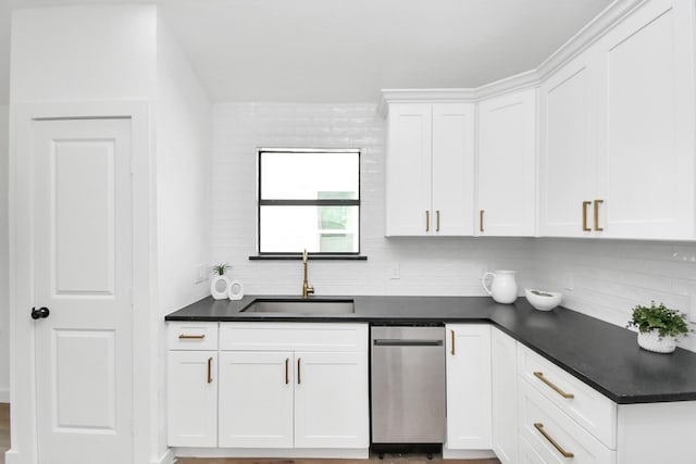 kitchen with dark countertops, white cabinetry, a sink, and backsplash