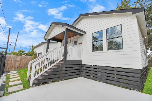 view of front of house with a patio, stairway, and fence