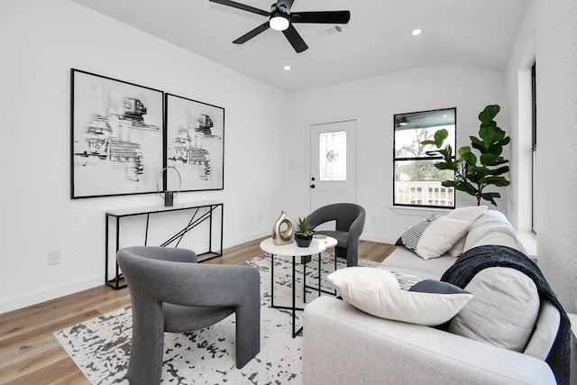 living room featuring light wood-type flooring, visible vents, lofted ceiling, and baseboards