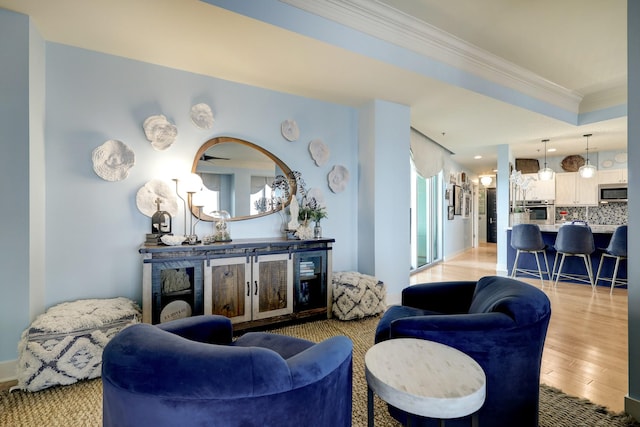 living room with a raised ceiling, light wood-type flooring, and ornamental molding