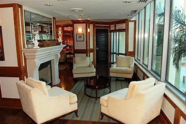 living area with a glass covered fireplace, visible vents, and wood finished floors