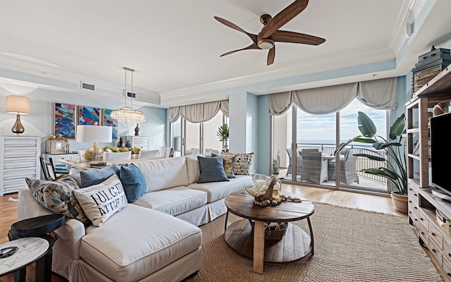 living area featuring ceiling fan with notable chandelier, visible vents, light wood finished floors, and ornamental molding