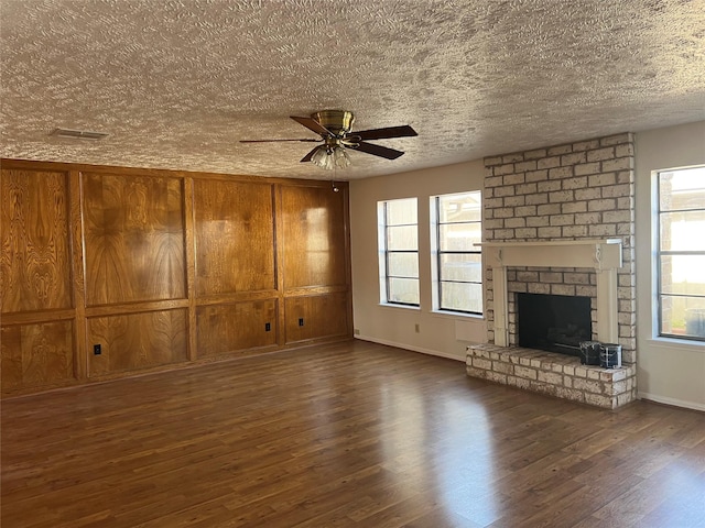 unfurnished living room featuring a brick fireplace, wood finished floors, and a ceiling fan