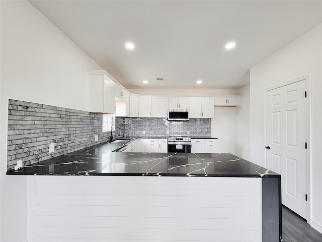 2731 Rd 5724, Cleveland, TX 77327 - kitchen with stainless steel appliances, a peninsula, white cabinets, tasteful backsplash, and dark wood finished floors