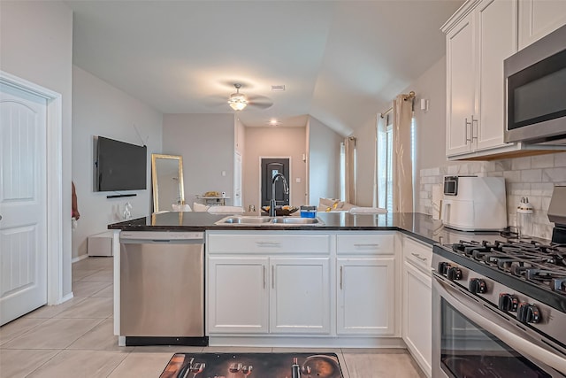 kitchen with light tile patterned floors, appliances with stainless steel finishes, a peninsula, a ceiling fan, and a sink