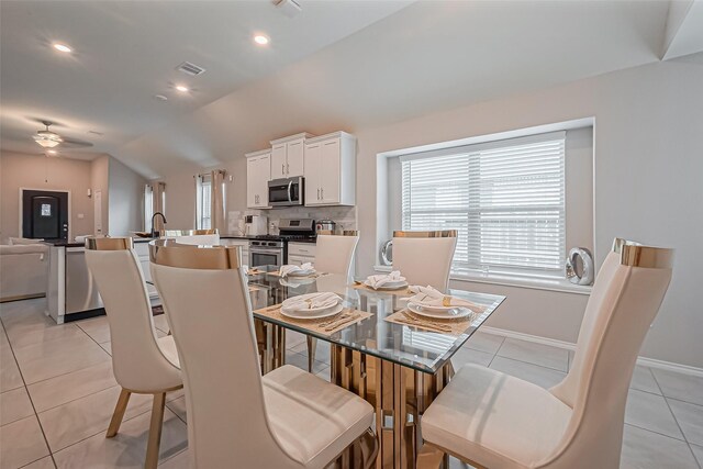 dining space featuring visible vents, light tile patterned flooring, a ceiling fan, and vaulted ceiling