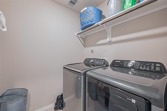 washroom featuring laundry area, separate washer and dryer, visible vents, and baseboards