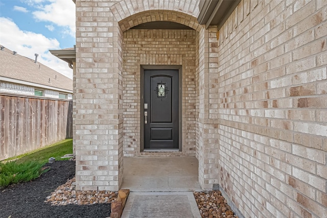 doorway to property with fence and brick siding