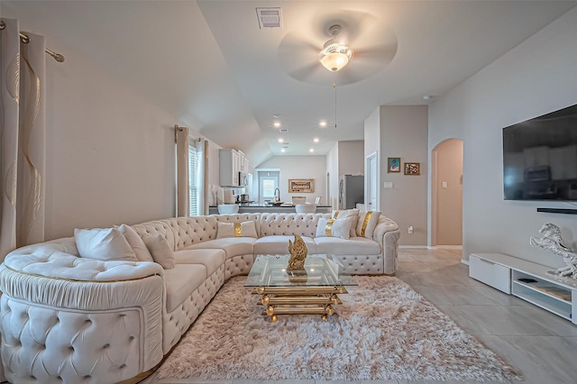 living room featuring light tile patterned floors, visible vents, lofted ceiling, arched walkways, and ceiling fan