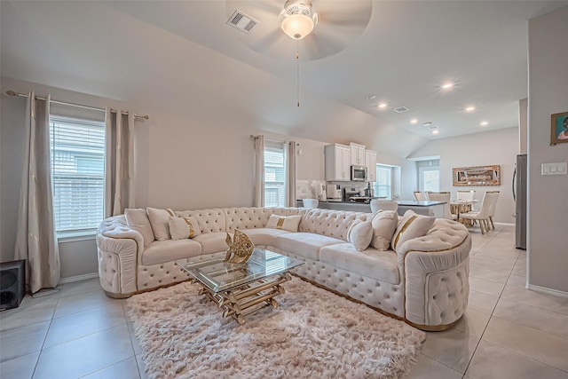 living room featuring light tile patterned floors, visible vents, lofted ceiling, and a ceiling fan