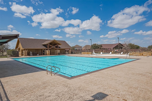 pool with a patio area and fence