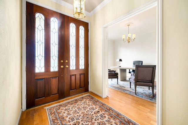 foyer with an inviting chandelier, wood finished floors, baseboards, and ornamental molding