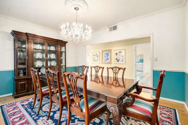 dining room featuring visible vents, baseboards, light wood-style floors, crown molding, and a notable chandelier