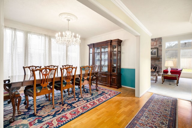 dining area featuring crown molding, wood finished floors, a fireplace, and a chandelier