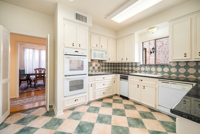 kitchen featuring white appliances, light floors, visible vents, dark countertops, and backsplash