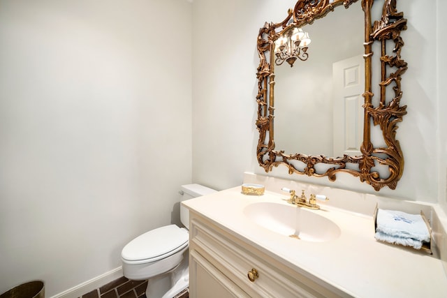 bathroom with toilet, vanity, and baseboards