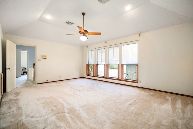 spare room featuring visible vents, light colored carpet, baseboards, and vaulted ceiling