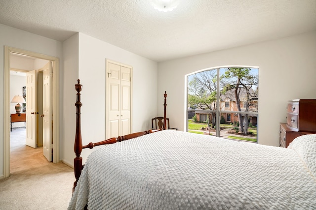 bedroom featuring a textured ceiling, a closet, and light carpet