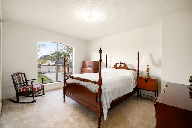 bedroom with light colored carpet and a textured ceiling