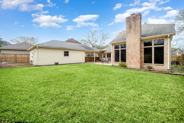 rear view of house with a yard, fence, a chimney, and a patio area