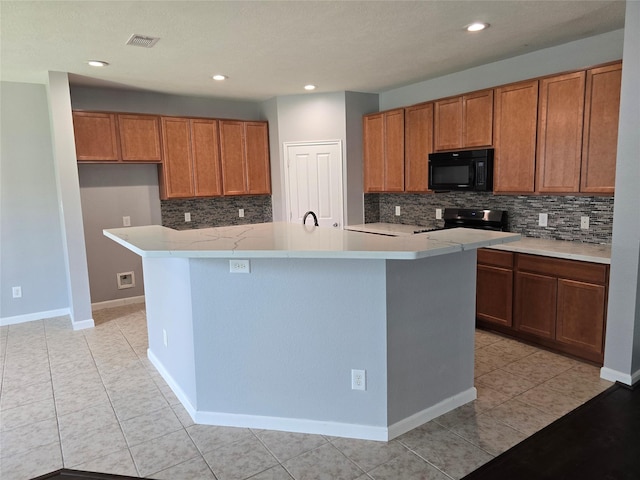 kitchen with visible vents, black microwave, brown cabinets, and stainless steel range with electric cooktop