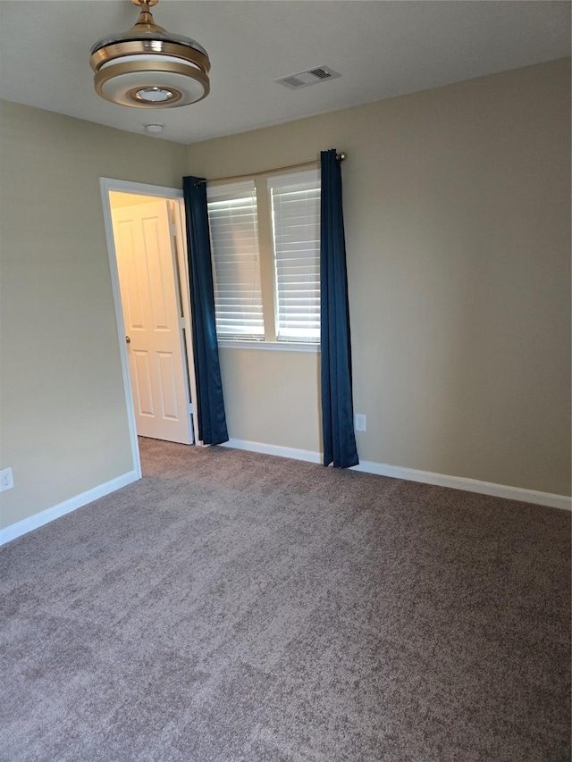 unfurnished room with carpet, visible vents, and baseboards