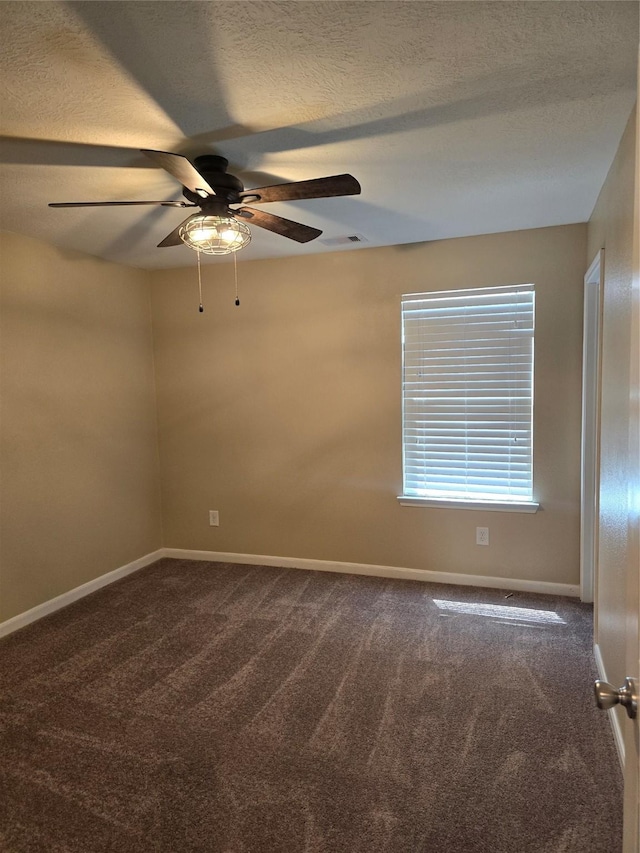 empty room featuring a textured ceiling, ceiling fan, baseboards, visible vents, and dark carpet