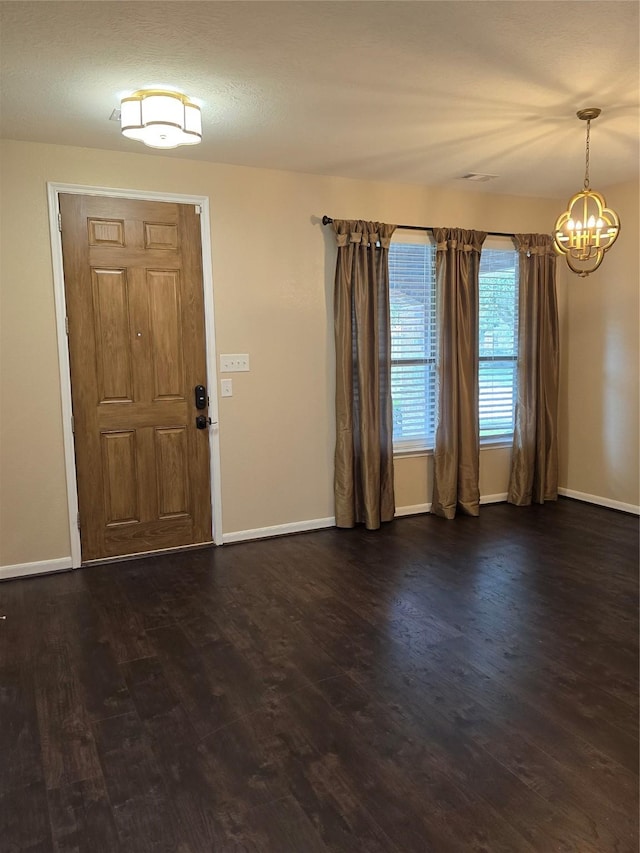 foyer entrance with dark wood-style flooring, baseboards, and an inviting chandelier