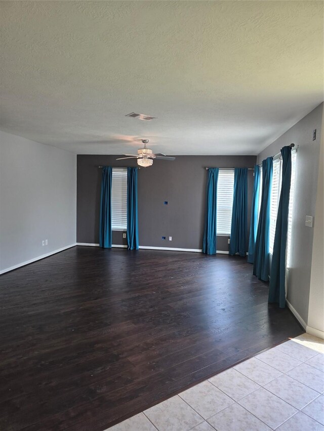 unfurnished room with a textured ceiling, ceiling fan, visible vents, and wood finished floors