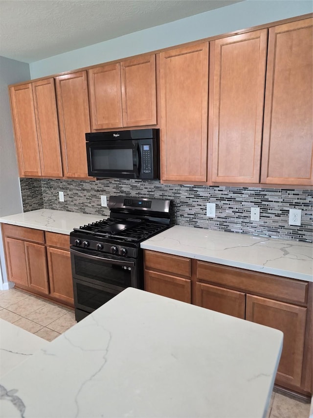 kitchen featuring black microwave, range with two ovens, backsplash, and light stone counters