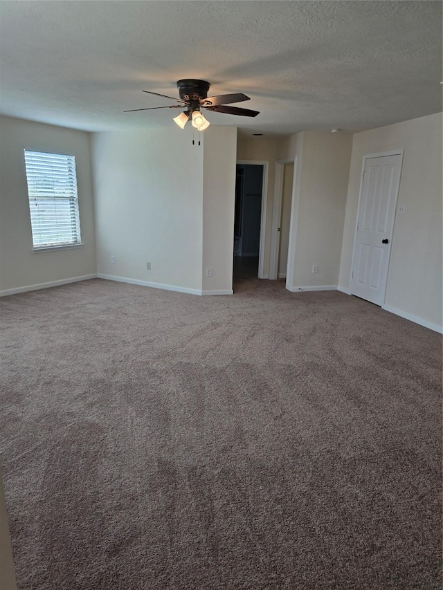 carpeted empty room featuring ceiling fan, a textured ceiling, and baseboards