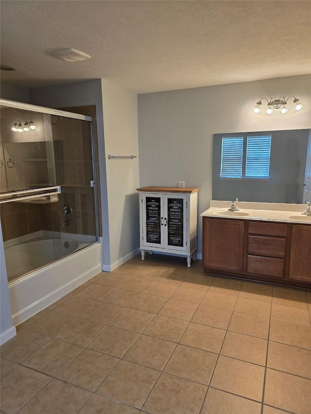 bathroom with tile patterned flooring, a textured ceiling, baseboards, and a sink