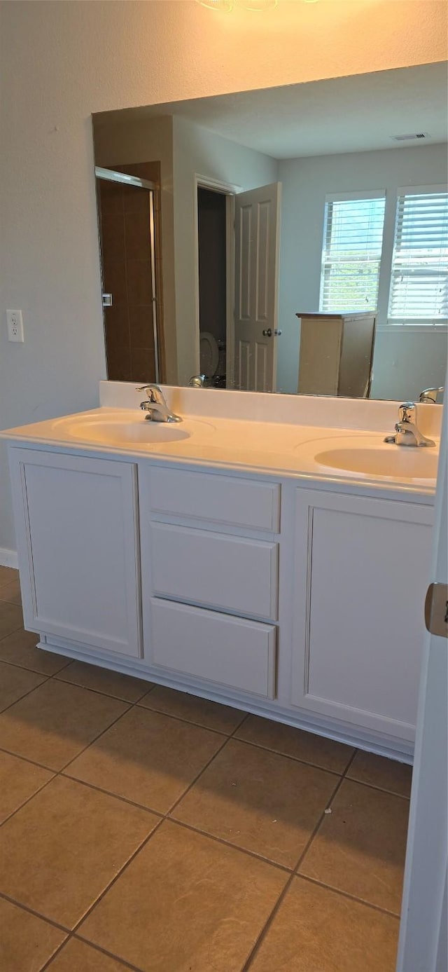 full bathroom with double vanity, a sink, tile patterned floors, and a shower stall