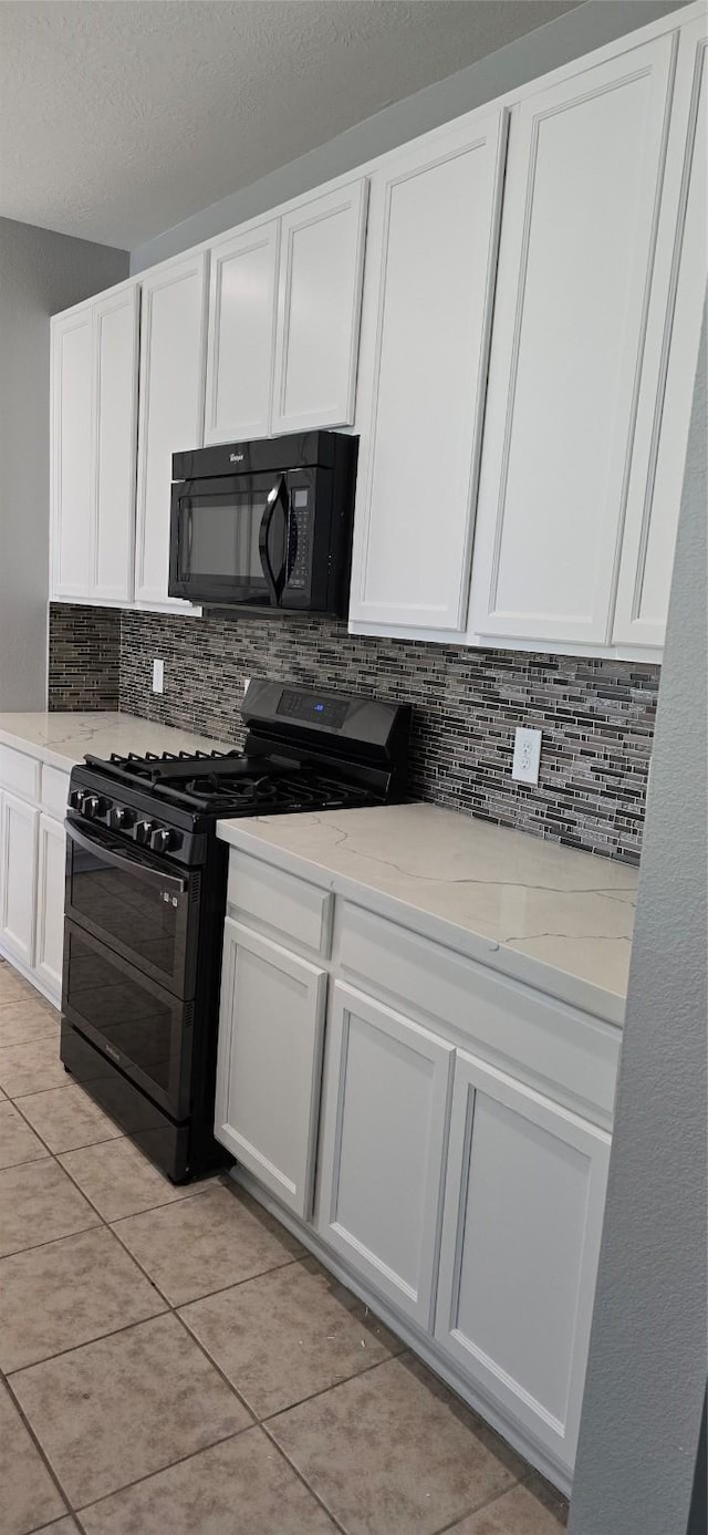 kitchen with white cabinetry, light stone counters, black appliances, and decorative backsplash