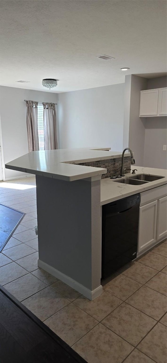 kitchen featuring a sink, a center island with sink, light tile patterned floors, black dishwasher, and white cabinets