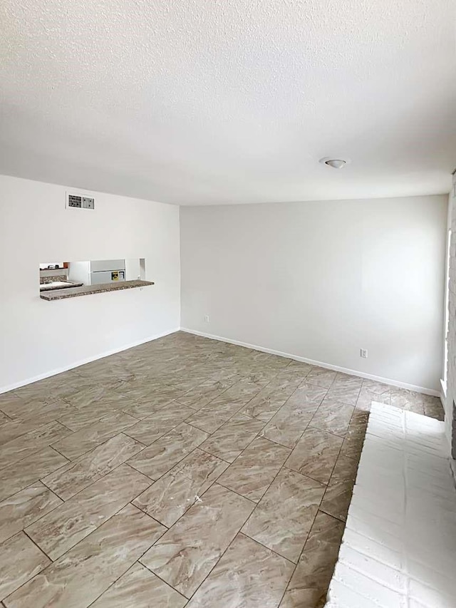 empty room featuring visible vents, baseboards, and a textured ceiling