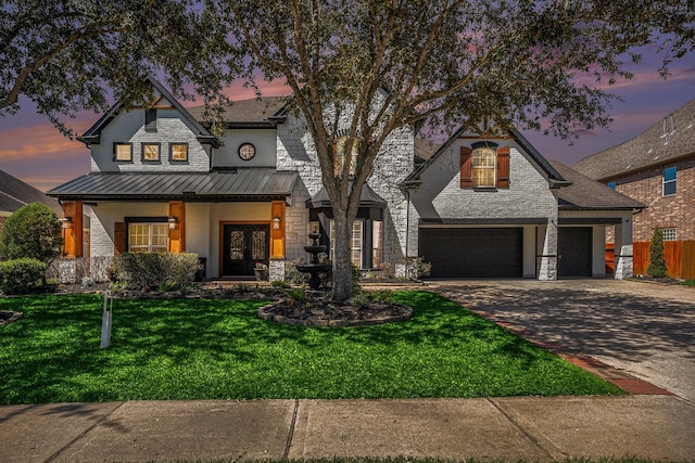 view of front of property featuring a standing seam roof, a front lawn, concrete driveway, stone siding, and metal roof