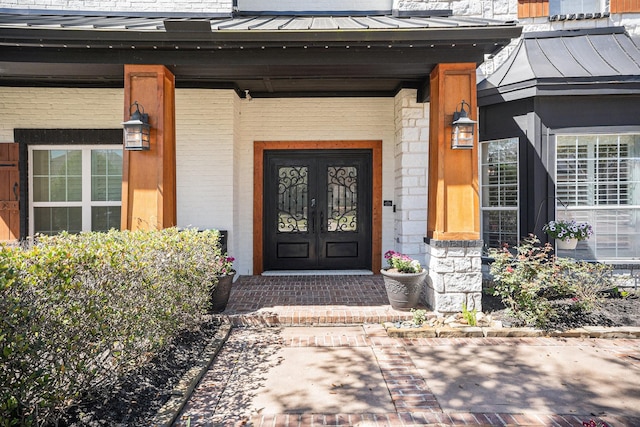 property entrance with a standing seam roof, covered porch, stone siding, and metal roof