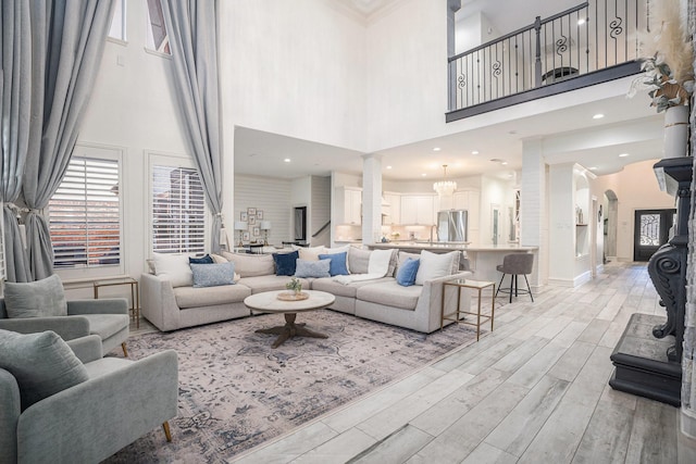 living room with baseboards, recessed lighting, a high ceiling, light wood-style floors, and arched walkways