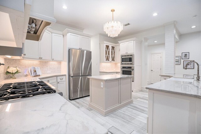 kitchen with glass insert cabinets, light wood-type flooring, light stone counters, stainless steel appliances, and white cabinetry