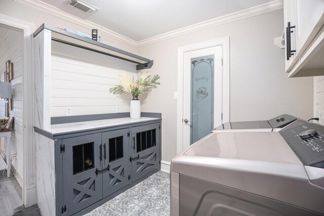 washroom featuring washer and dryer, cabinet space, visible vents, and ornamental molding