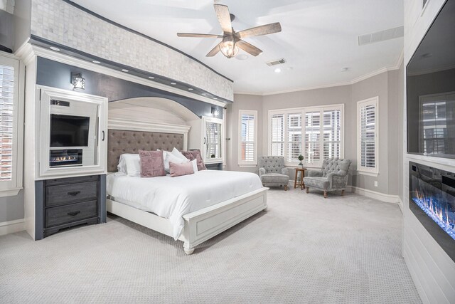 bedroom featuring visible vents, a glass covered fireplace, carpet floors, crown molding, and baseboards