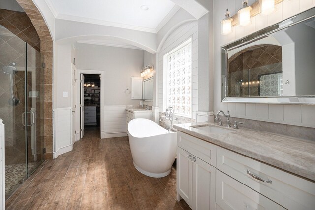 full bath featuring wood finished floors, a freestanding bath, ornamental molding, a shower stall, and a sink