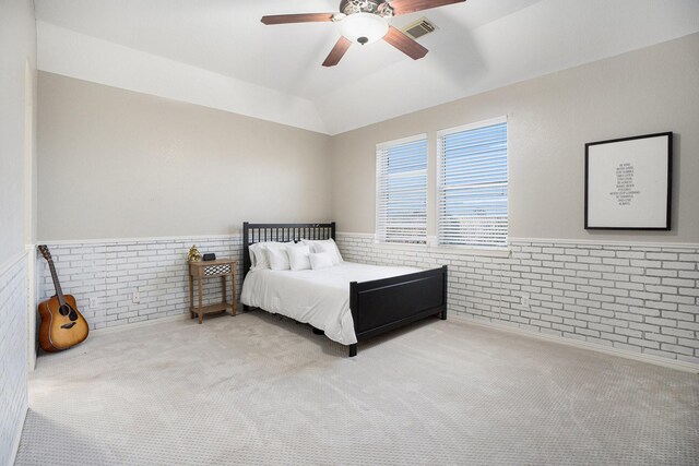 bedroom featuring a wainscoted wall, lofted ceiling, visible vents, and brick wall