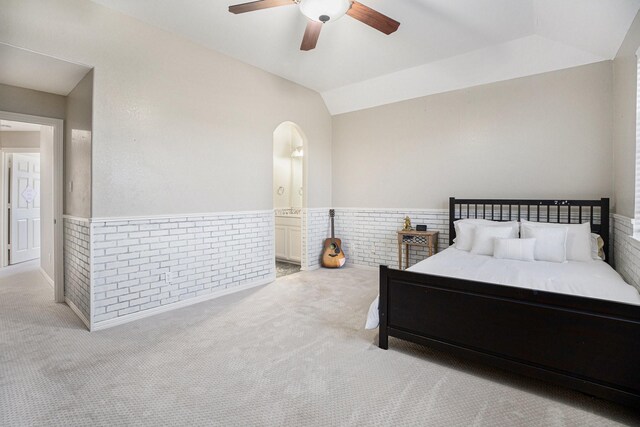 bedroom with carpet, a wainscoted wall, lofted ceiling, arched walkways, and ceiling fan