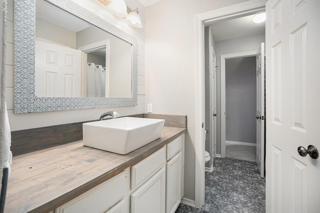 bathroom with vanity, toilet, and baseboards